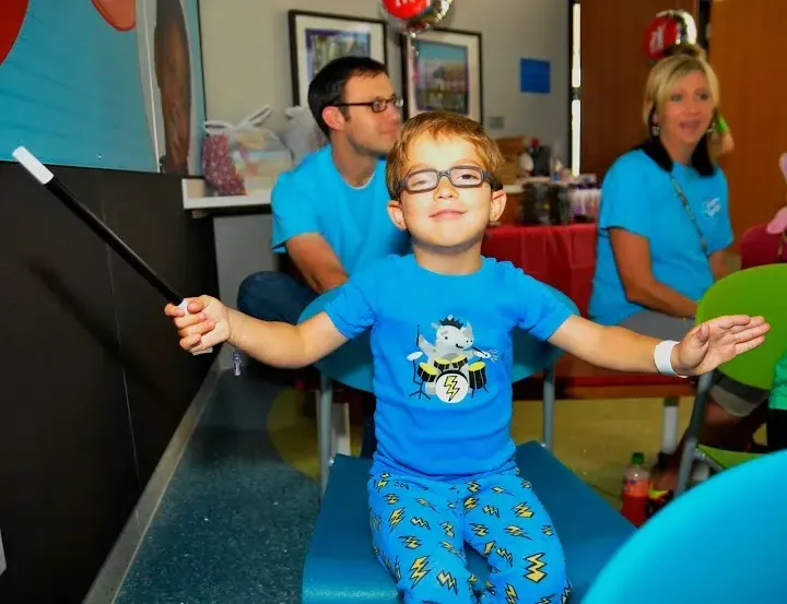 A young patient with his arms outstretched during a hospital visit