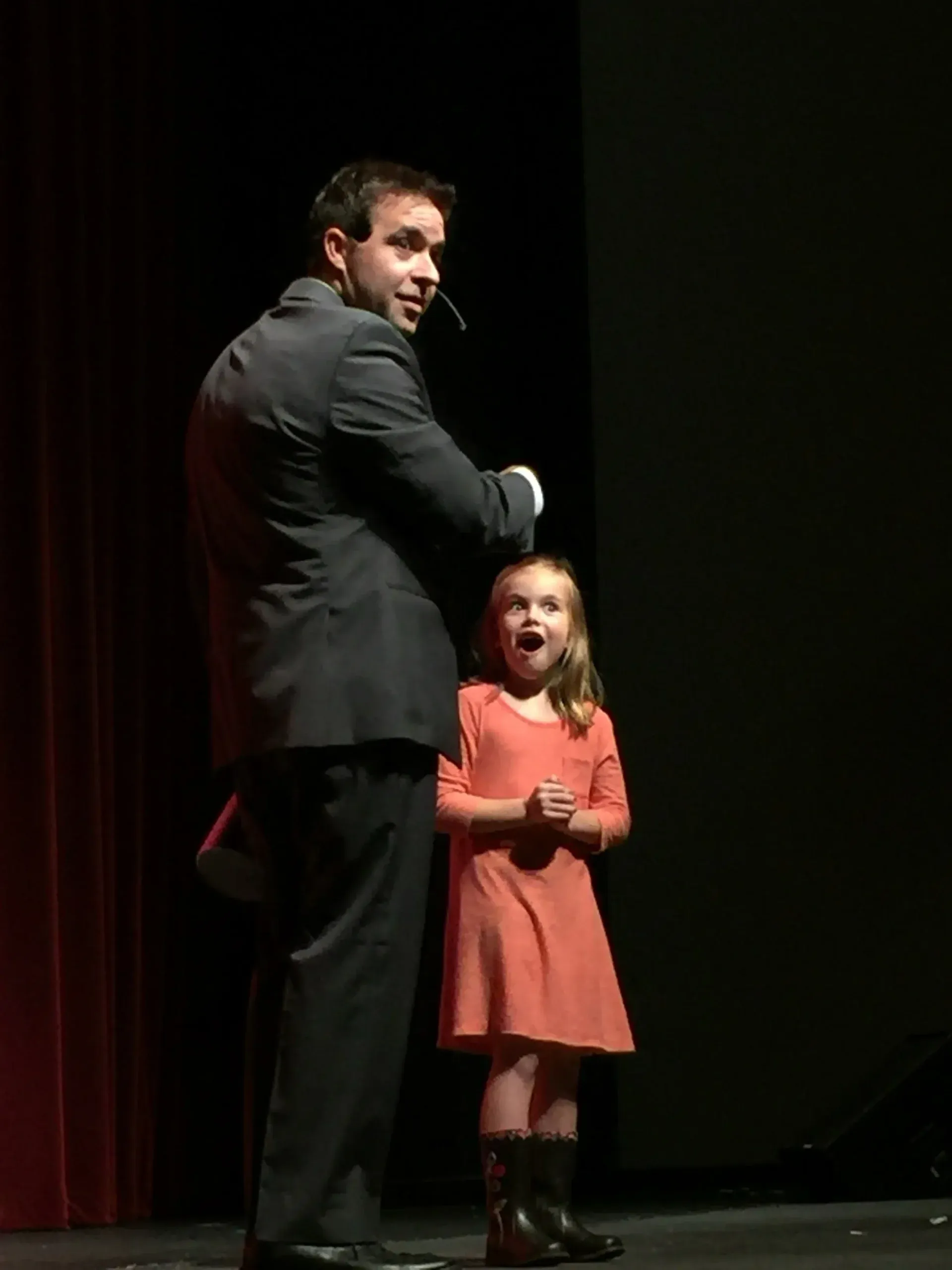 A girl on stage reacting open-mouthed beside Matt