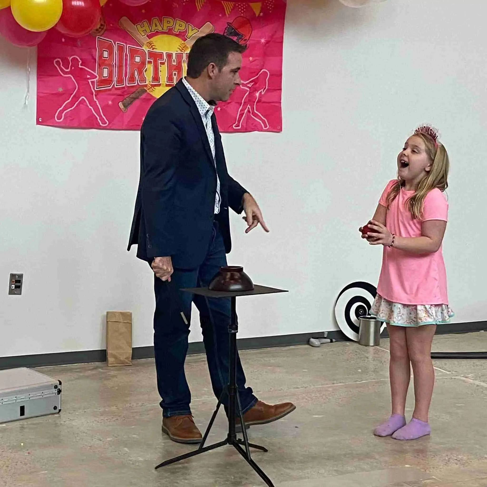 A girl in a party tiara reacting to a trick at a birthday show