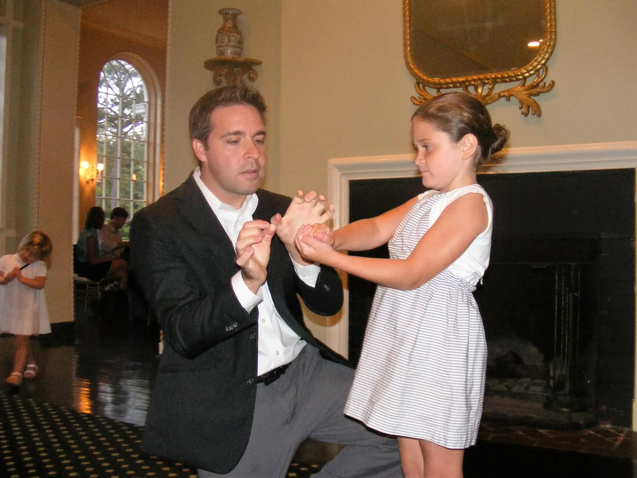 Matt kneeling to show a trick to a young girl at a parlor show