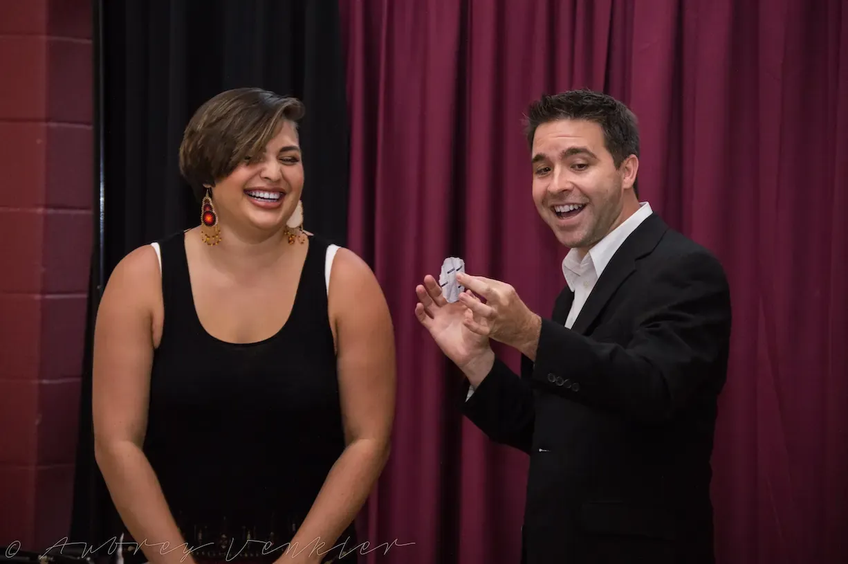 A guest laughing beside Matt during a parlor show