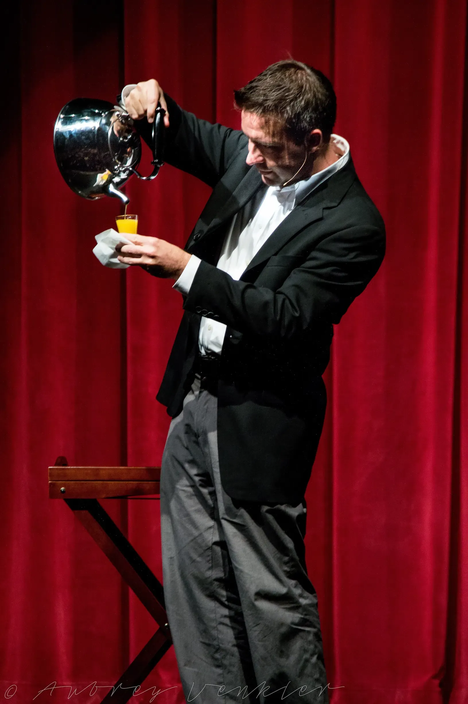 Matt in tails pouring from a top hat in front of a red stage curtain